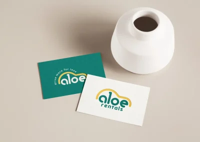 Aloe Rentals business cards, green and white, with car logo and tagline, beside a vase. Brand and Web Design Gold Coast.