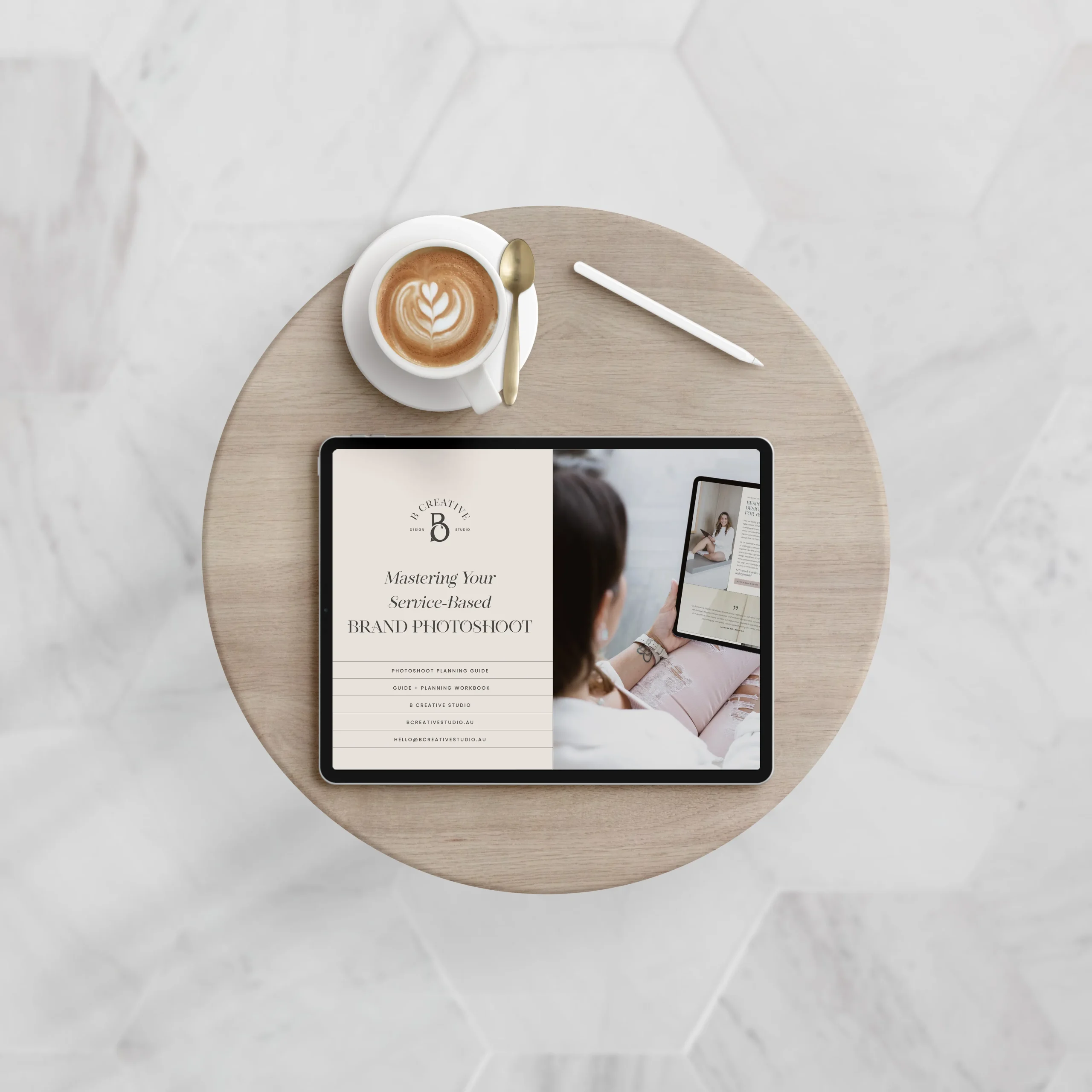 A round wooden table with a tablet displaying a free guide to master your brand photoshoot, a latte with heart-shaped foam art, and a white stylus, all set on a light, patterned floor background. A round wooden table with a tablet displaying a free guide to master your brand photoshoot, a latte with heart-shaped foam art, and a white stylus, all set on a light, patterned floor background.