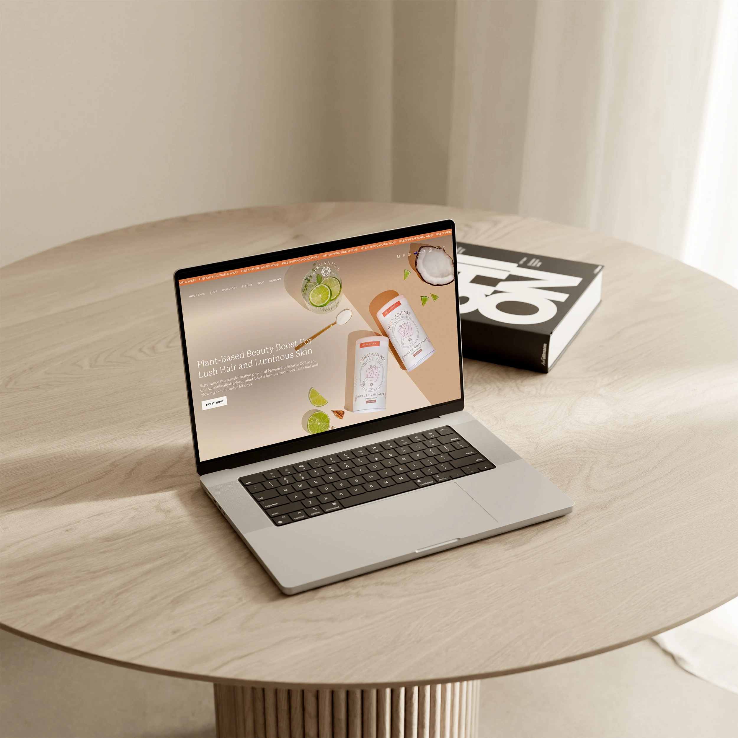 A laptop displaying a website with plant-based beauty products sits on a round wooden table next to a closed black and white book in a softly lit room with beige curtains. A laptop displaying a website with plant-based beauty products sits on a round wooden table next to a closed black and white book in a softly lit room with beige curtains.